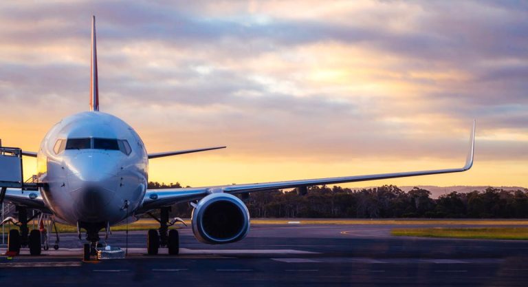 Sunset view of airplane on airport runway under dramatic sky.