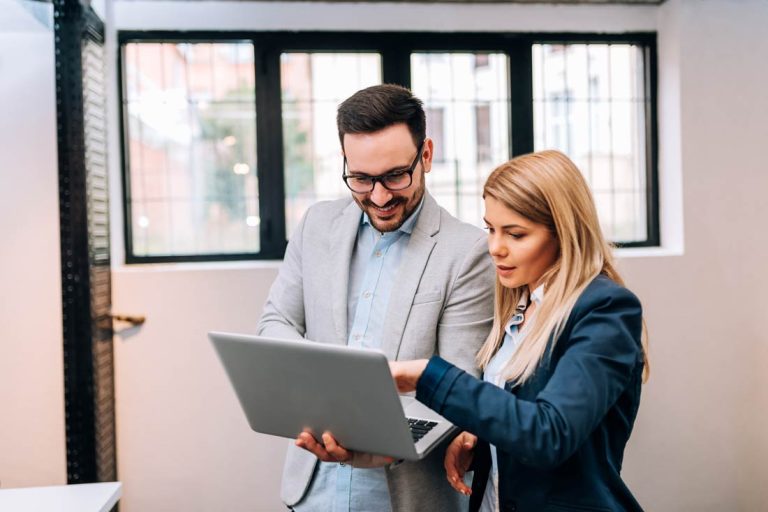 Young business man holding a laptop while discussing new project with his female colleague