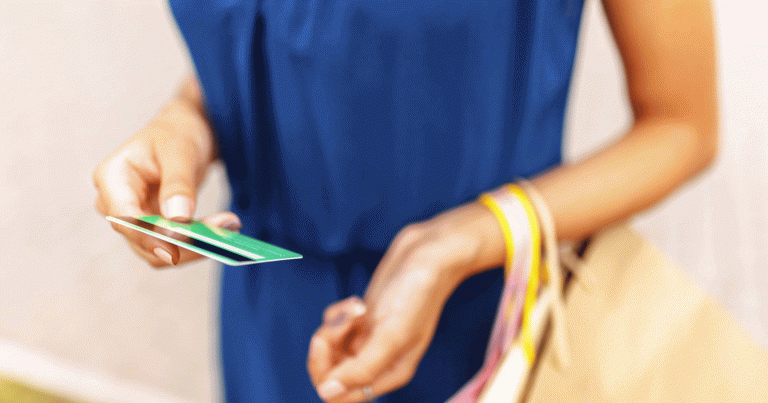 Woman in dress holding shopping bags and credit card for payment