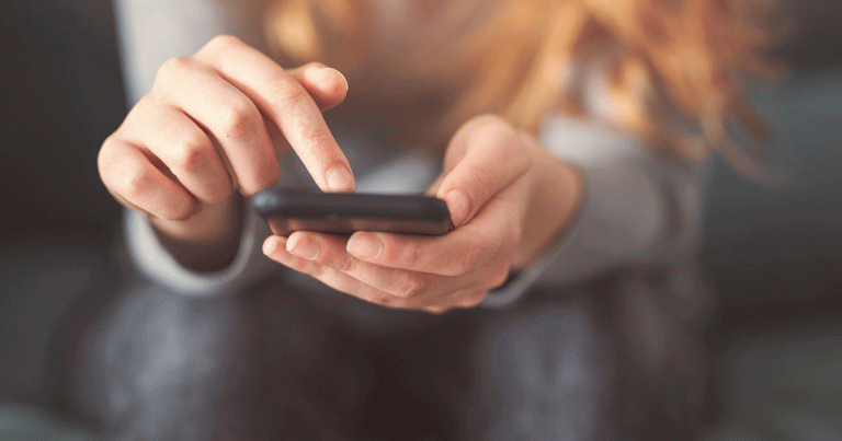 Girl holding smartphone in her hands using a mobile app