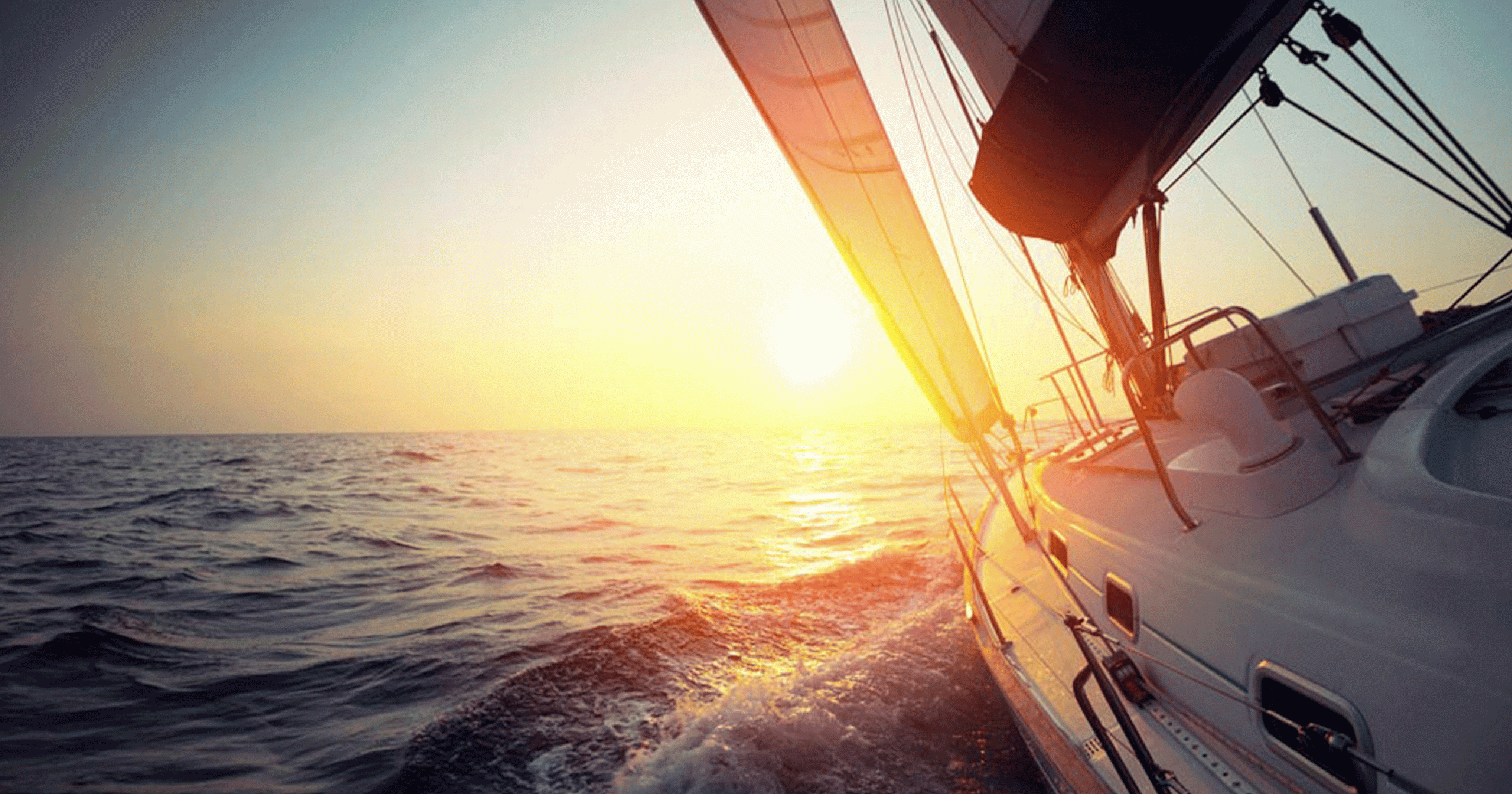 Sailboat moving towards the horizon at sunset