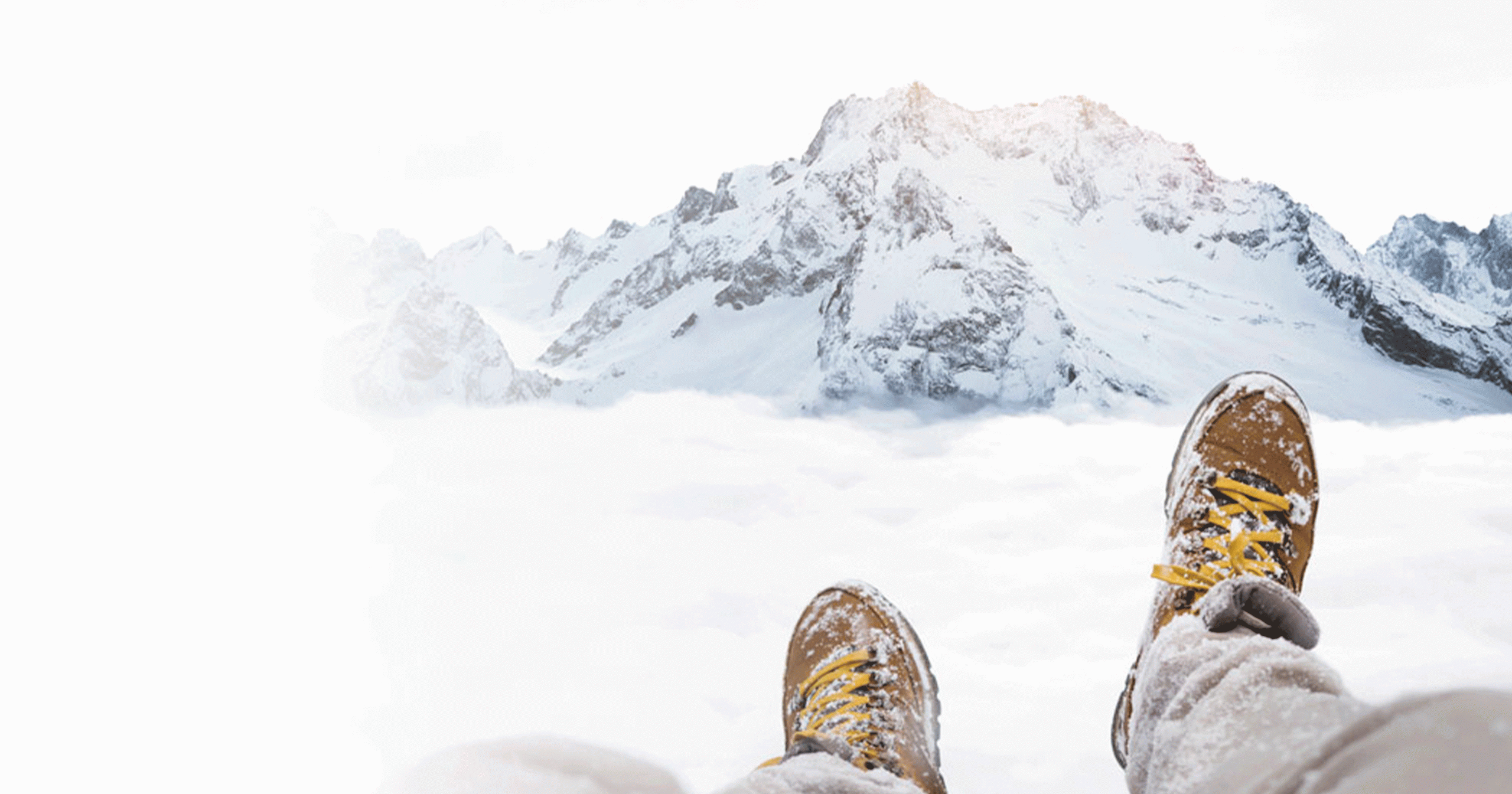 Image of persons legs and boots sitting on top of a snowy mountain