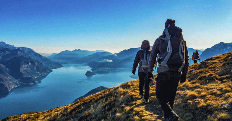 Hikers in backpacking gear on mountain overlooking lake